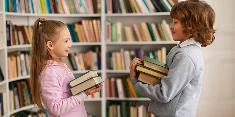 Kitap takası etkinliğinde kitaplarını değiş tokuş eden okurlar ve takas masası